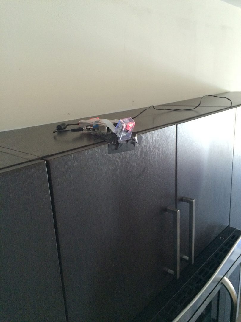 Figure 1: Mounting the Raspberry Pi to the top of my kitchen cabinets.